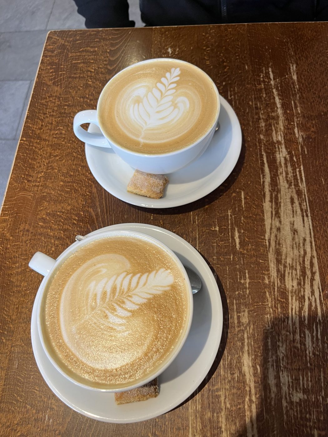 Two lattes with latte art on a wooden table