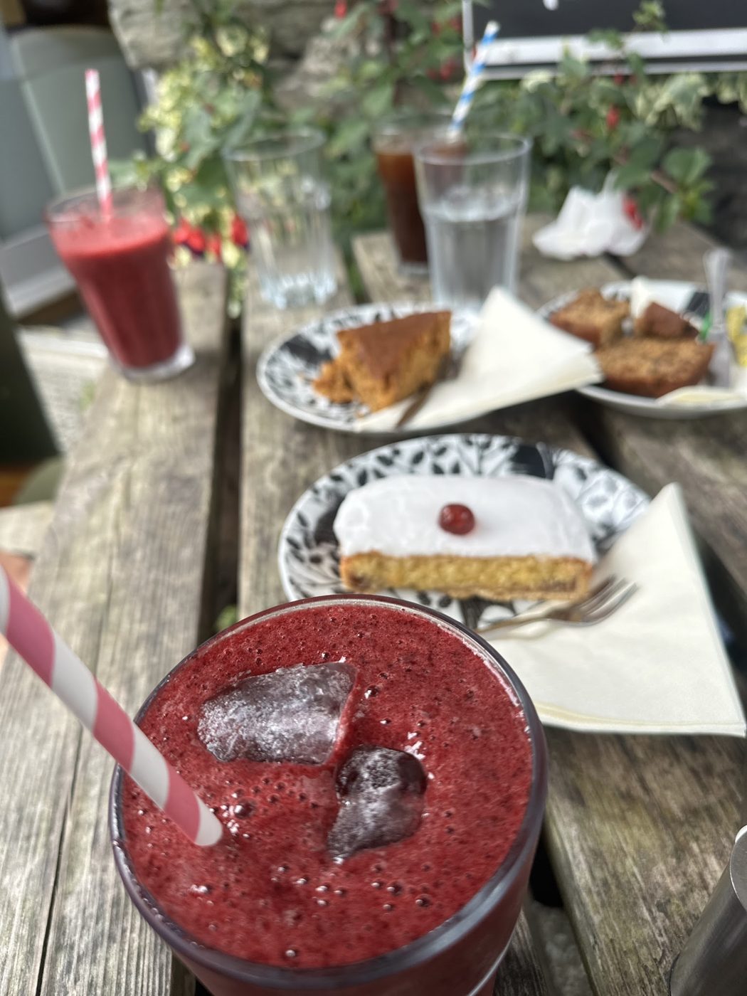 A berry smoothie with slices of cake on an outdoor table
