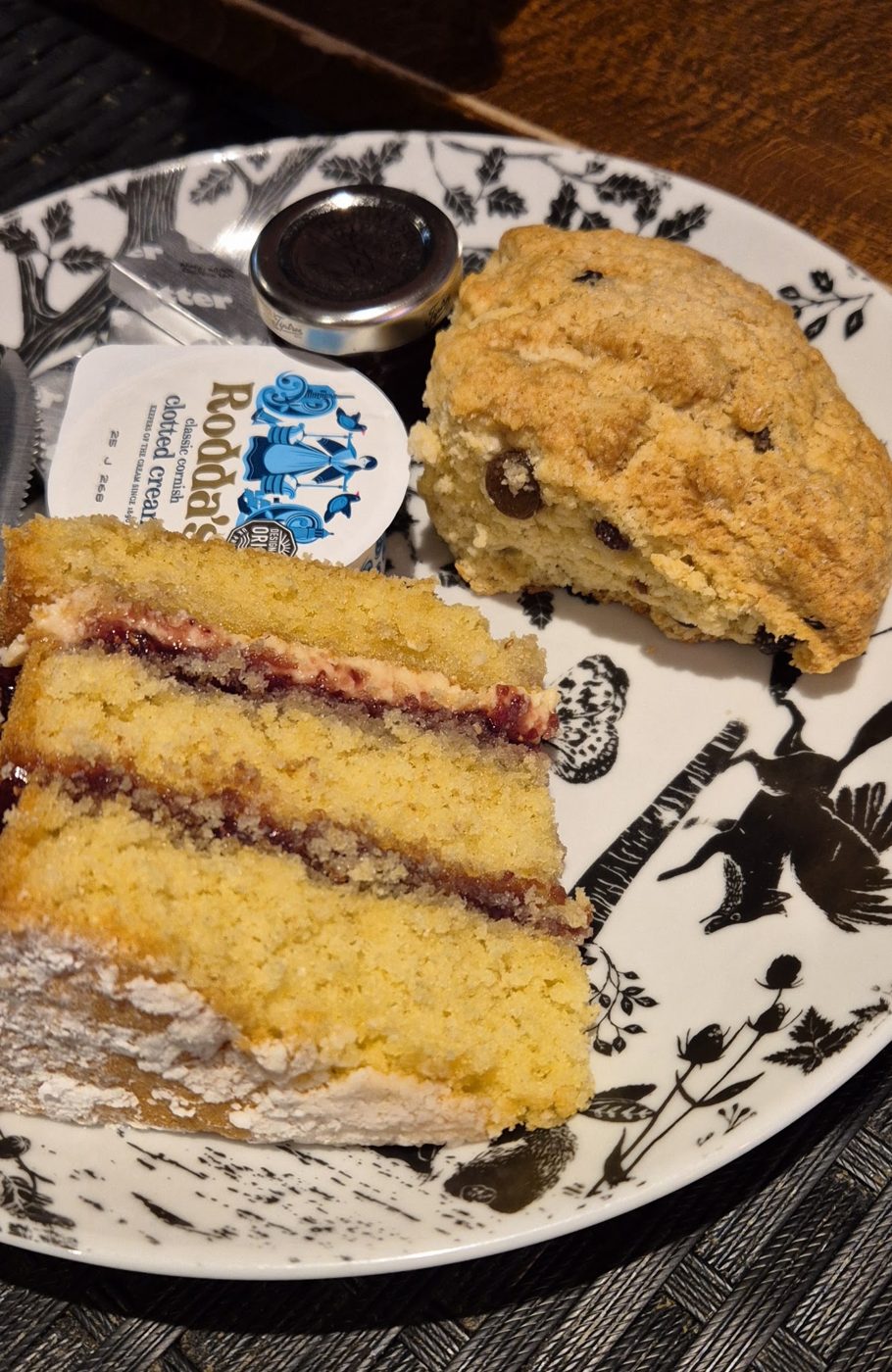 A slice of jam sponge cake and a scone with butter